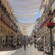 A city street shaded by sheets and lined with storefronts, street lights and people
